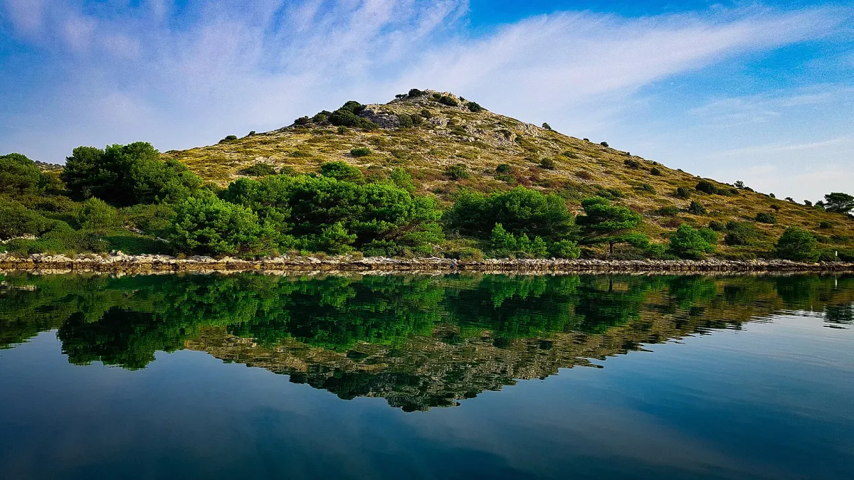 Ein grünes Inselchen im Kornaten-Archipel spiegelt sich im stillen Wasser